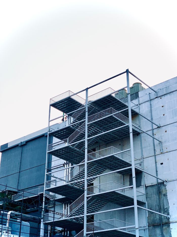 A contemporary building featuring an external metal staircase in an urban setting.